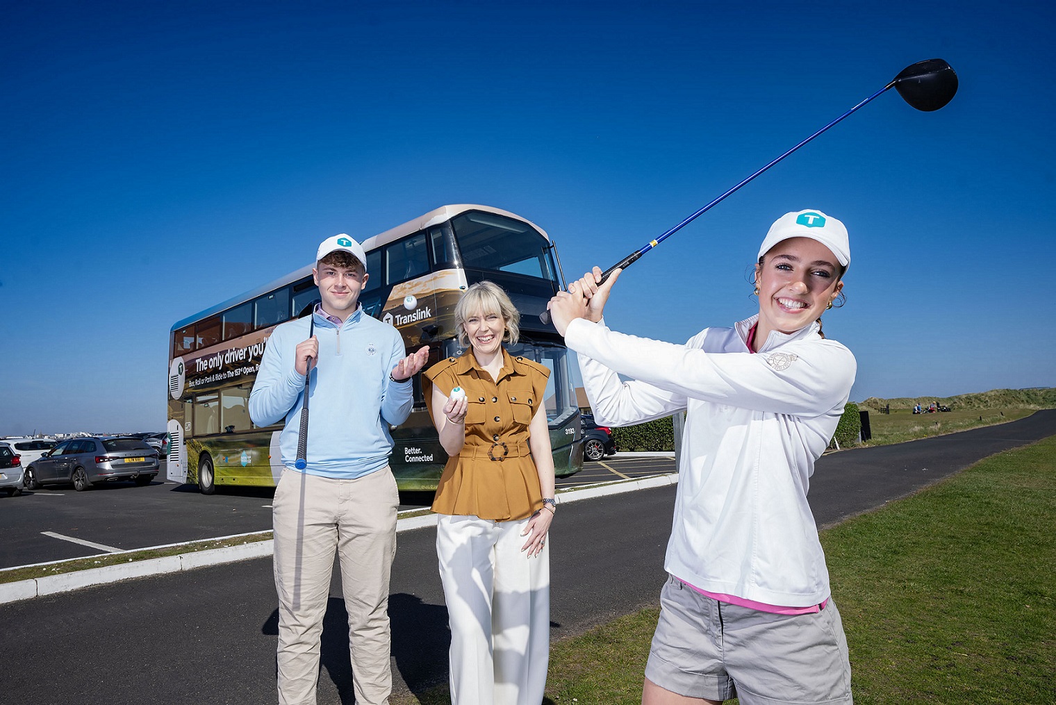 A woman swings a gold club in front of a Translink bus at the announcement of Translink travel options for the 153rd Open