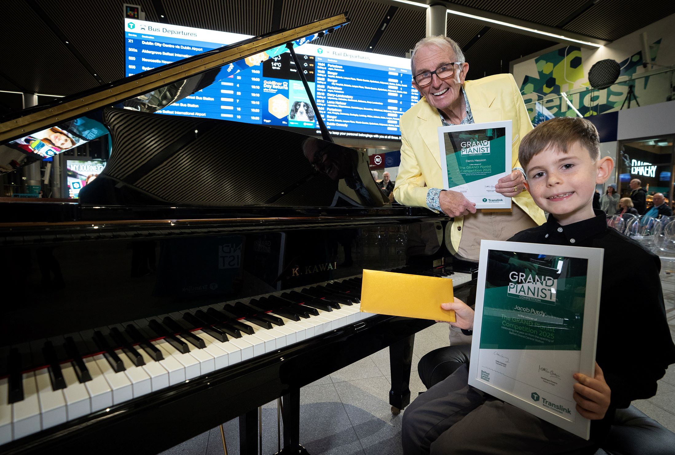 The winners of Translink's Grand Pianist competition with a piano in Belfast Grand Central Station