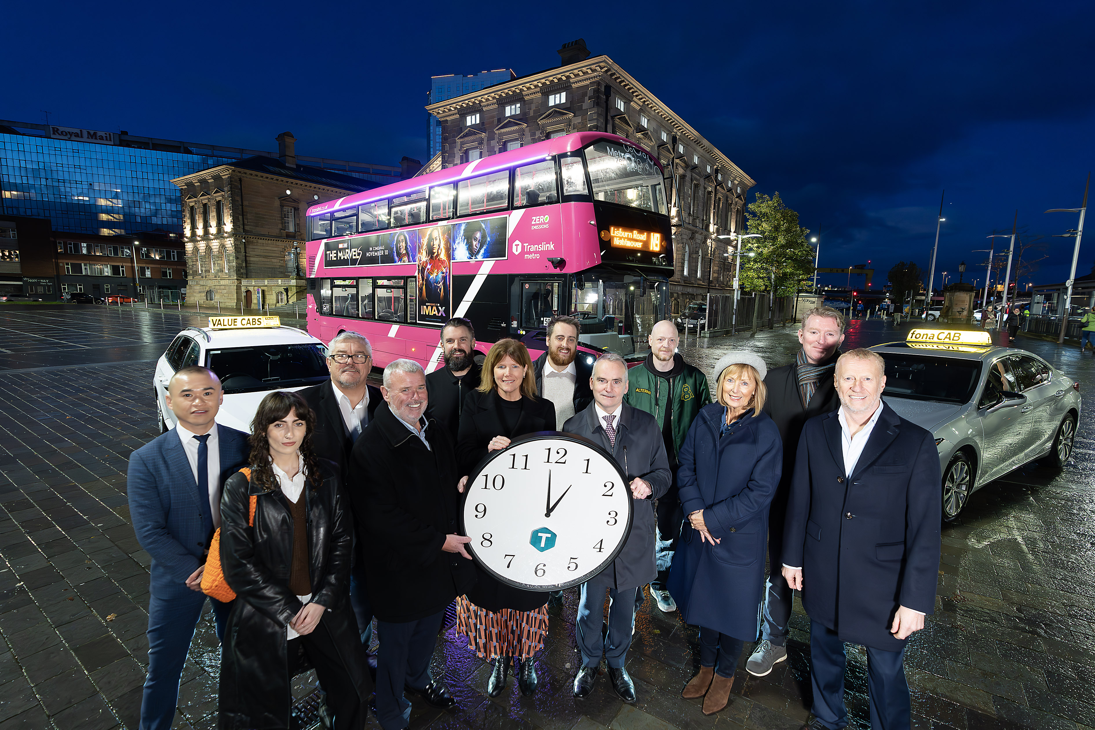 Translink staff standing in front of a Metro bus at night