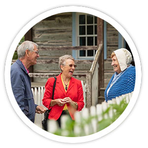 A man and woman are talking to a lady in historical costume at the Ulster American Folk Park